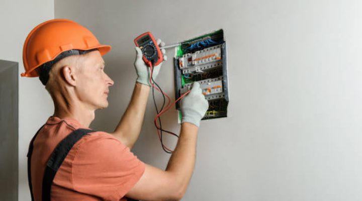The electrician is checking with a multimeter the correctness of the connection of the circuit breaker.